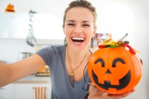 mom holding a jack-o-lantern bucket full of Halloween candy