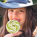 girl in a witch costume eating a lollipop on Halloween